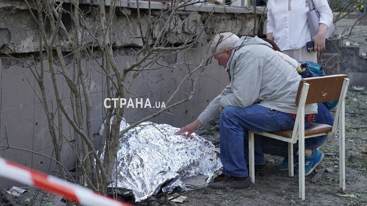 Погибшая в Киеве девочка и ее дедушка, который сидит у тела ребенка. Фото